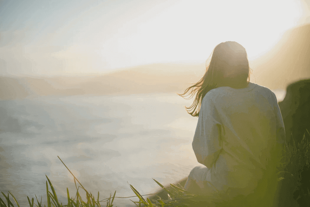 woman sitting next to a lake