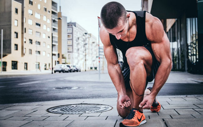 guy on a run tying his shoes