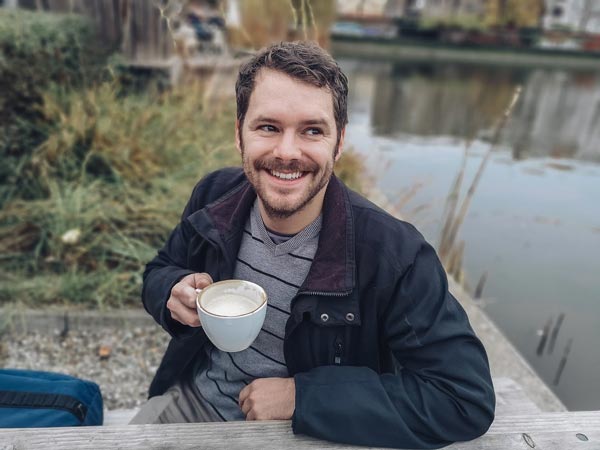 man smiling with coffee cup outside